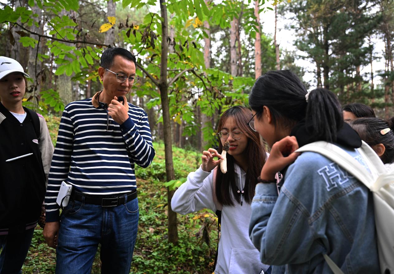 王占斌老師給同學(xué)們講解辨識蘑菇。（學(xué)校供圖）.jpg