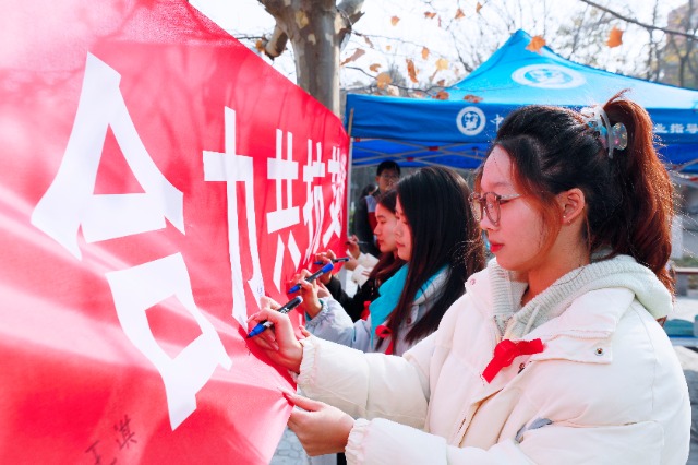 20231127中國(guó)石油大學(xué)（華東）青年學(xué)子在合力共抗艾滋的條幅上簽字，表達(dá)抗擊艾滋病的決心和信心  .jpg