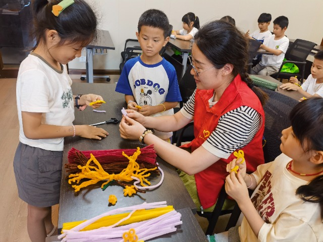 7月12日，在泰州市海陵區(qū)城東街道林湖社區(qū)，泰州市大浦小學(xué)“綠葉”暑期公益班的老師正在教孩子們一起做手工2（拍攝者：泰州市大浦中心小學(xué)  陳惠婷）.jpg